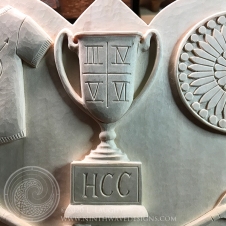 Upper center: Shows the Hugh Camp Cup, with Roman numerals III, IV, V, VI, representing that the cup was won by a member of the Form of 2019 each of their four years.